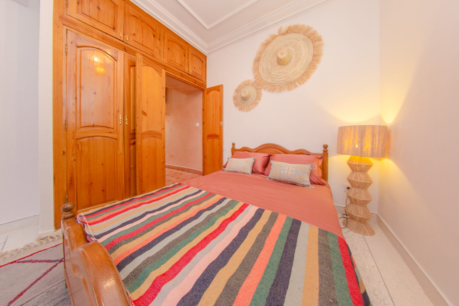 The Marrakech room: wooden bed, striped rug and rose-toned walls