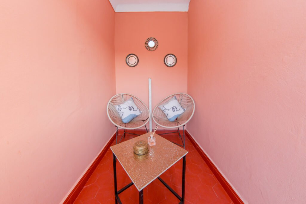 Two wrought-iron armchairs against a rose-pink wall