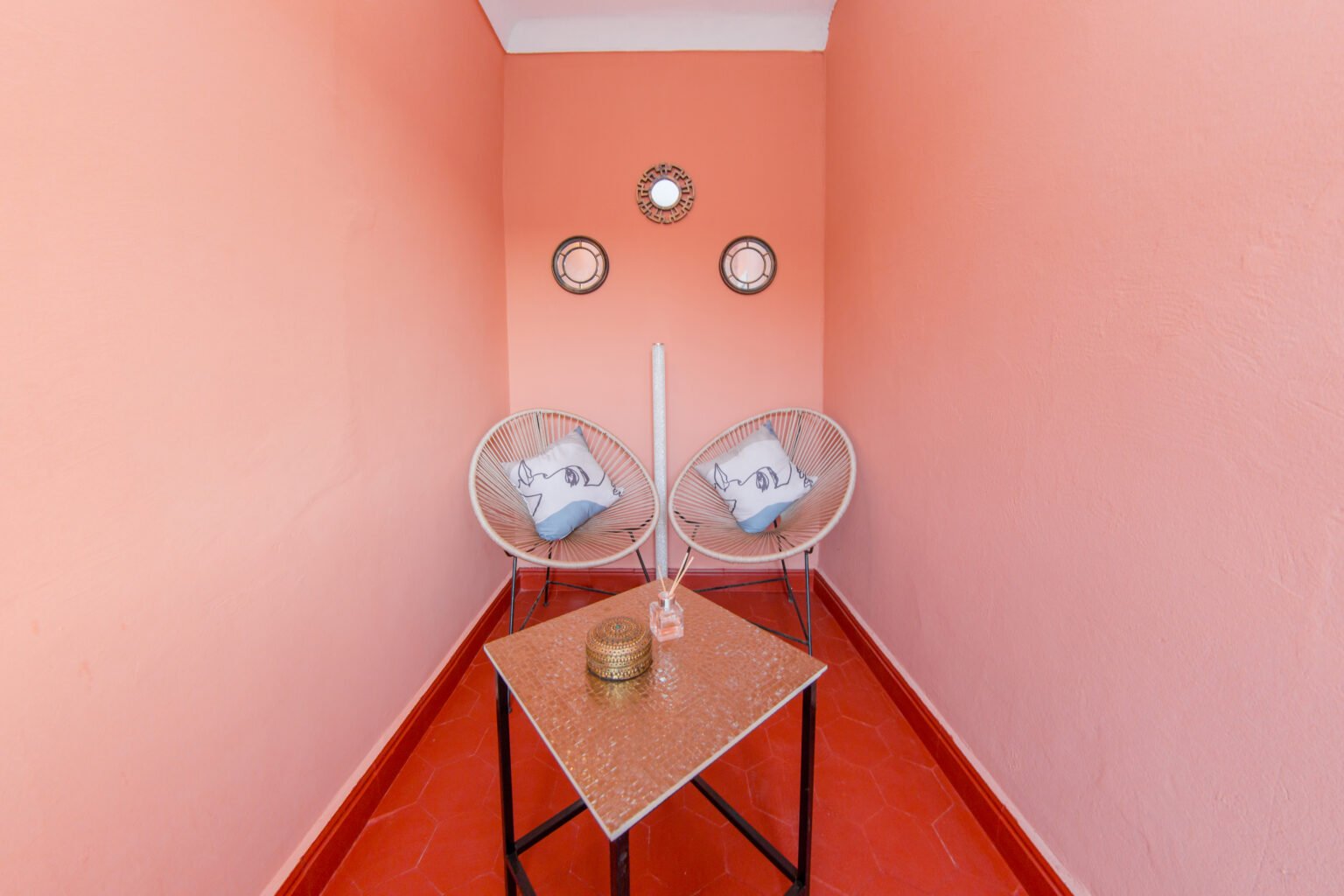 Deux fauteuils en fer forgé contre un mur rose