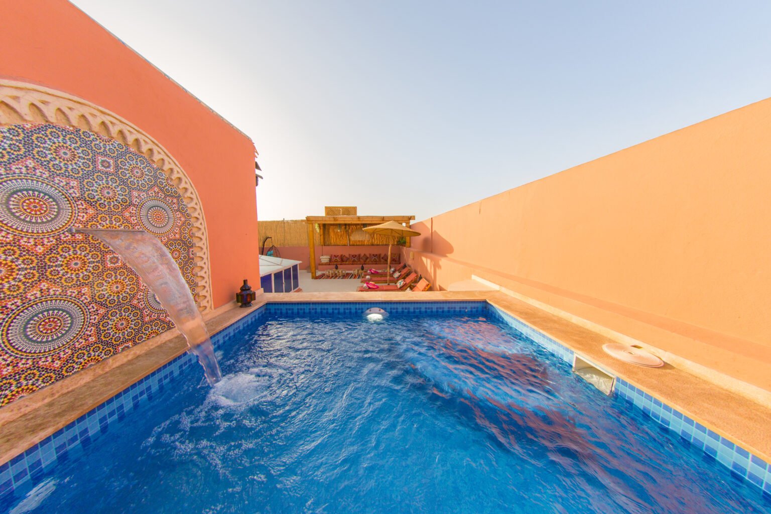 La piscine de la terrasse entre les murs roses du riad