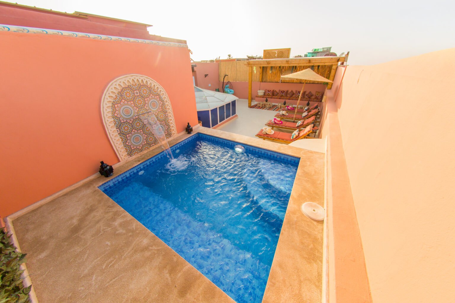 The rooftop pool, between rose-pink walls and a zellige fountain